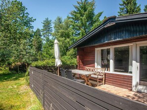 A cabin with a deck, a table, and chairs. - 4 Person Holiday Home in Norre Nebel (Norre Nebel)