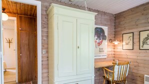 A room with a wooden ceiling, a light green wardrobe, a wooden chair, and a poster on the wall. - 4 Person Holiday Home in Norre Nebel (Norre Nebel)