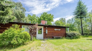 A rustic cabin with a wooden exterior, a white door, and a sign reading 'DUNELA'. - 4 Person Holiday Home in Norre Nebel (Norre Nebel)