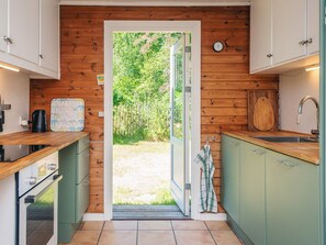 Eine Küche mit Holzwänden, einem großen Fenster und Blick auf Grün.