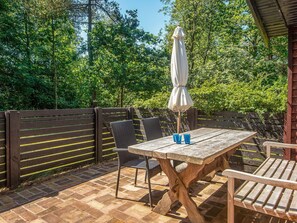 An outdoor patio with a wooden table, two chairs, and a white umbrella. - 4 Person Holiday Home in Norre Nebel (Norre Nebel)