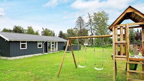 A residential property with a wooden swing set, a playhouse, and a house with a metal roof. - Holiday Home in VÃ¦ggerlÃ¸se (Vaeggerlose)