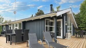 A modern outdoor deck with a dining table and chairs, a grill, and a covered seating area. - Holiday Home in VÃ¦ggerlÃ¸se (Vaeggerlose)