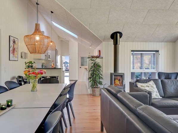 Eine moderne Küche mit Essbereich, Kamin und Wohnzimmer mit Sofa und Pflanze.