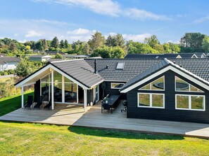 Een modern huis met een ruim terras, een overdekte patio en een zwembad.