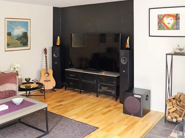 A living room with a black entertainment unit, a guitar, a table with a bowl, and a fireplace.