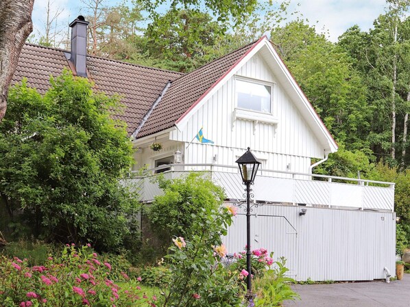 A white house with a red roof, a balcony, and a garden with pink flowers. - Tranquil Coastal Retreat in Halland-by Traum (Vallda)