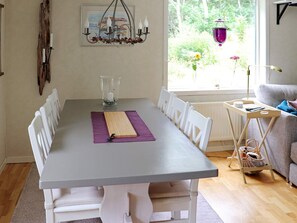 A dining area with a table, chairs, a chandelier, and a view of greenery outside. - Tranquil Coastal Retreat in Halland-by Traum (Vallda)