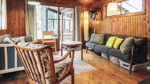 A cozy cabin interior with wooden walls, a sofa, a chair, and a table. - 8 Person Holiday Home in Vaeggerlose (Vaeggerlose)