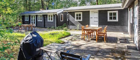 A cabin with a patio, outdoor seating, and a grill.