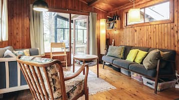 A cozy cabin interior with wooden walls, a sofa, a chair, and a table.