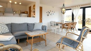 A cozy living room with a sofa, a coffee table, wicker chairs, and a dining area with a table and chairs. - Holiday Home in FanÃ¸ (Fano)
