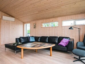 A modern living room with a black leather sofa, a wooden coffee table, and a black armchair.