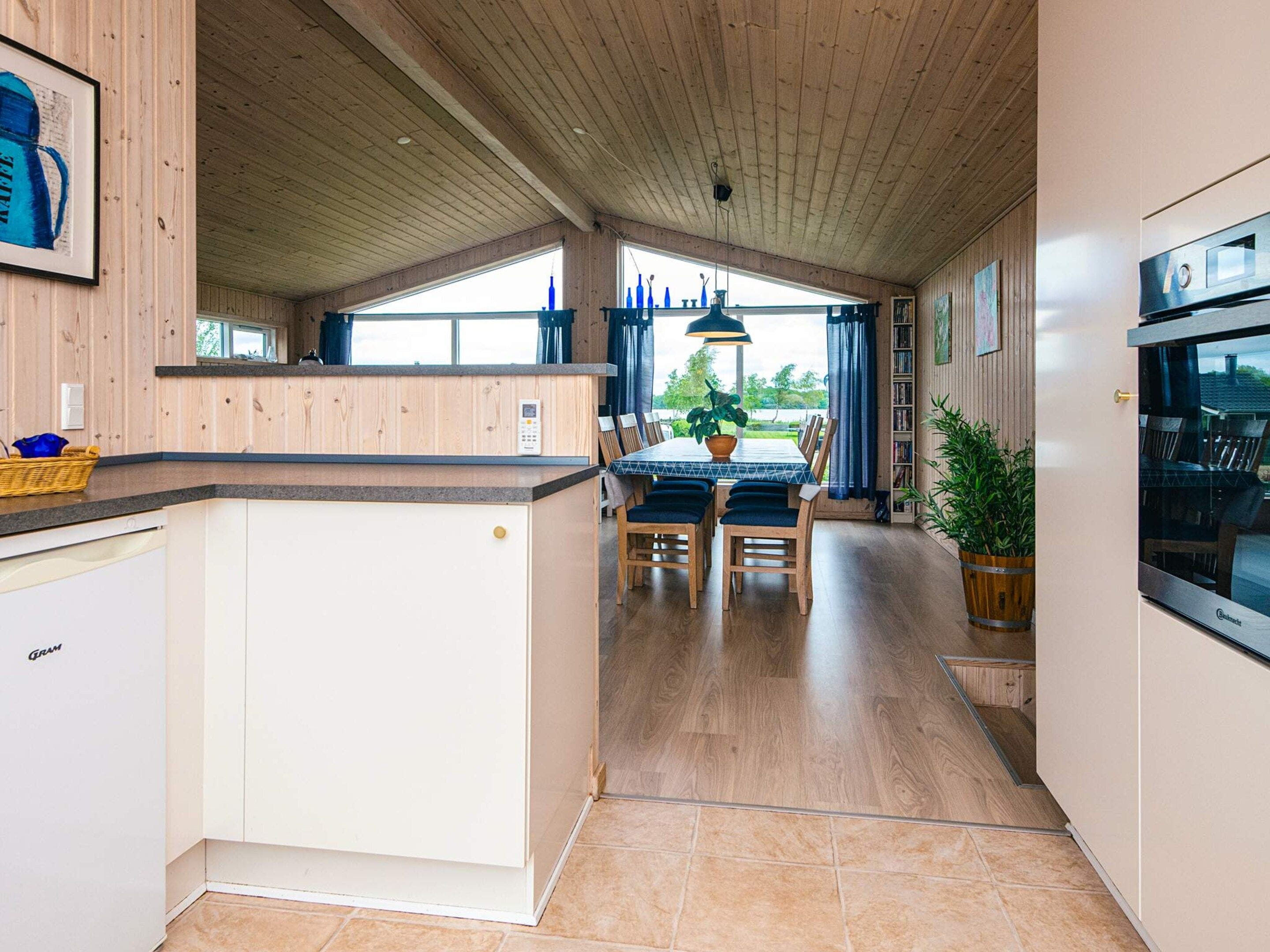 Een ruime keuken met houten kastjes, een eethoek met een tafel en stoelen, en uitzicht op de omgeving.