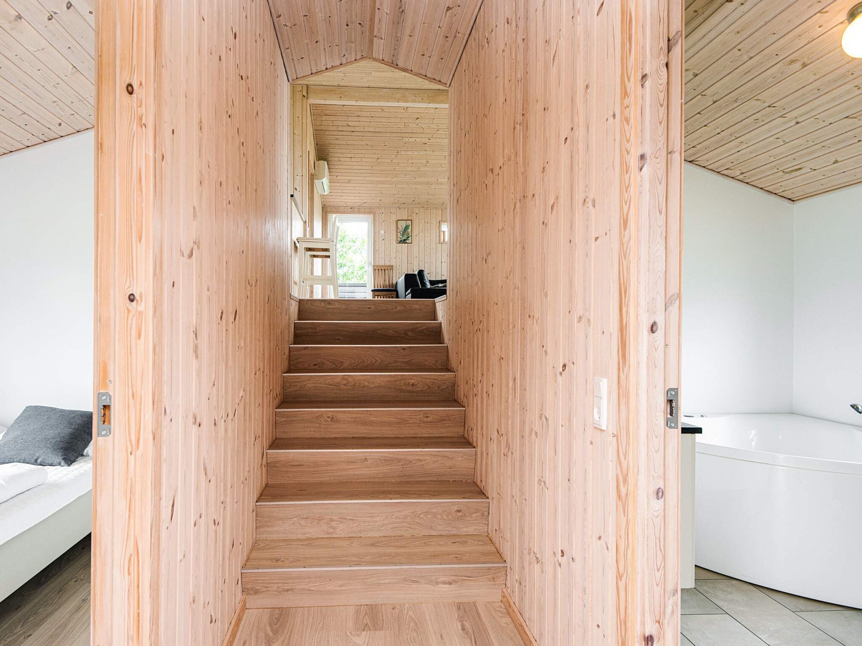 Una escalera de madera conduce a una sala de estar con un sofá y una mesa de comedor.