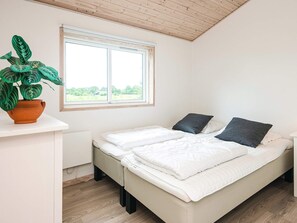 A bedroom with a bed, a window, and a potted plant.