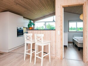 A modern kitchen with wooden cabinets, a built-in oven, and a window overlooking greenery.