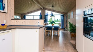 Una cocina moderna con armarios de madera, una isla central y un comedor con vistas al exterior.