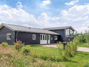 A two-story house with a dark exterior, a tiled roof, and a front door. - Holiday Home in Ansager (Ansager)