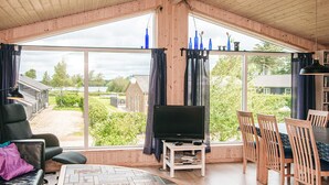 Un salón amplio con un gran ventanal, televisor de pantalla plana, una mesa de centro y muebles de madera.