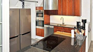 A modern kitchen with stainless steel appliances, wooden cabinets, and a built-in gas stove.