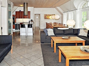 En rummelig opholdsstue med et moderne køkken, et spisebord og en sofa.