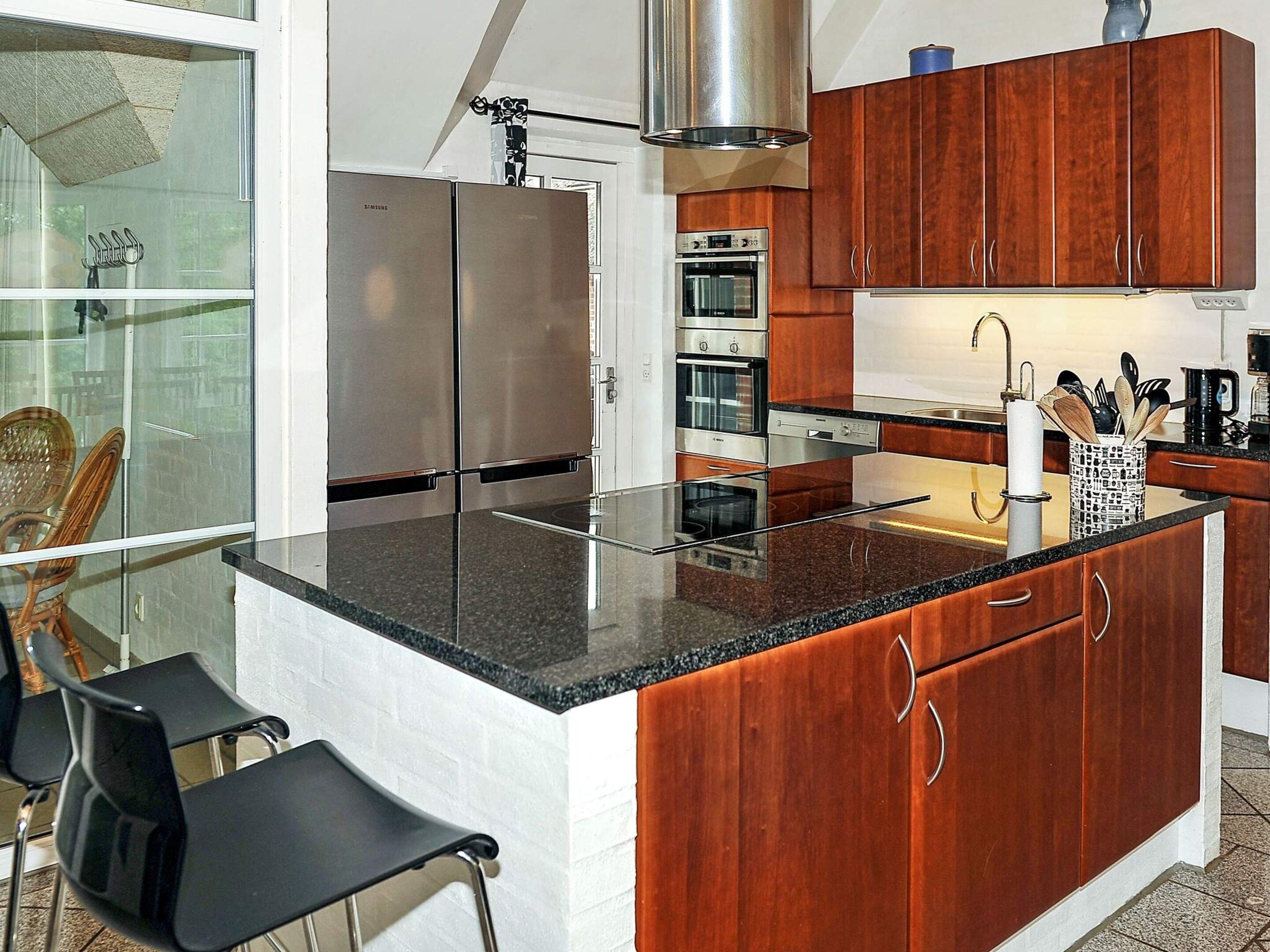 A kitchen with stainless steel appliances, wooden cabinets, and a glass island.