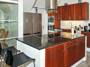 Una cocina con electrodomésticos de acero inoxidable, armarios de madera y una isla de vidrio.