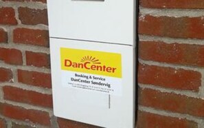 A white box with a yellow label that reads 'DanCenter Booking & Service DanCenter Sandervej.' - Holiday Home in Ulfborg (Ulfborg)
