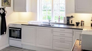 A kitchen with white cabinets, a built-in oven, a sink, and a window with a view of greenery. - Historic Water Tower Retreat-by Traum (Dannemare)
