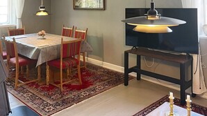 A dining area with a table set for four, chairs, a television on a stand, a rug, and a wall-mounted air conditioner. - Historic Water Tower Retreat-by Traum (Dannemare)