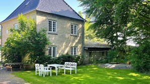 A stone building with a tiled roof, a grassy lawn, and outdoor furniture. - Historic Water Tower Retreat-by Traum (Dannemare)