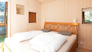A wooden-paneled room with a bed, two bedside lamps, and a small window. - Holiday Home in VÃ¦ggerlÃ¸se (Vaeggerlose)