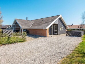A two-story house with a gravel driveway and a wooden fence. - Holiday Home in Juelsminde (Horsens)