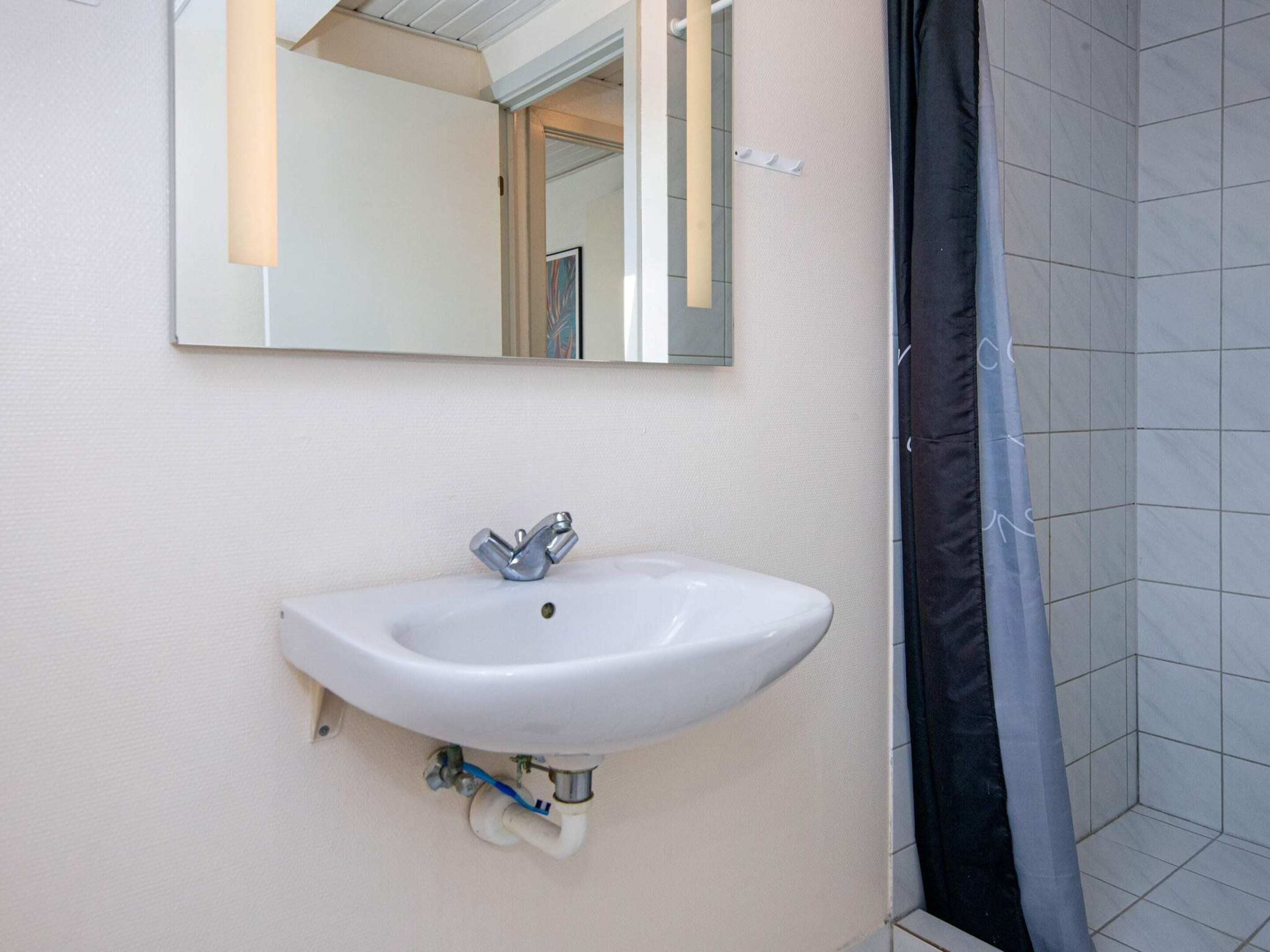 A bathroom with a white sink, a mirror, and a shower curtain.