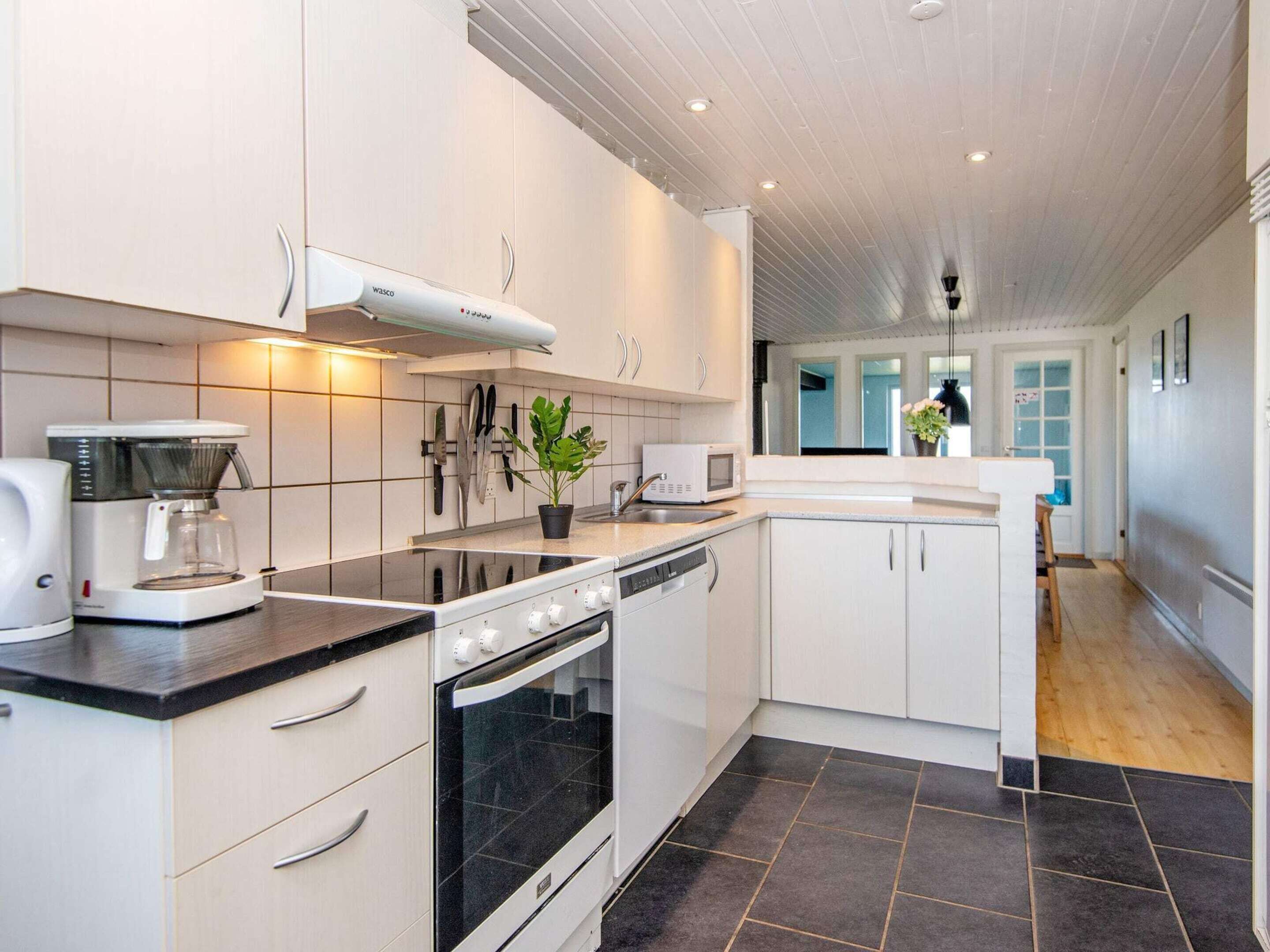 A modern kitchen with white cabinets, a black stove, a coffee maker, and a microwave.