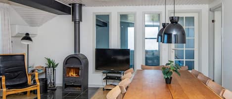 A modern living room with a fireplace, a dining table, and a TV.