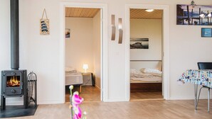A cozy room with a wood-burning stove, a bed, a desk, and a chair. - 4 Person Holiday Home in Norre Nebel (Norre Nebel)