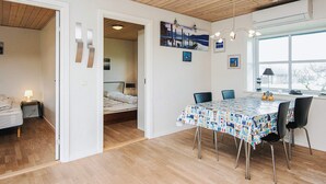 A room with a wooden ceiling, a bed with a nightstand, a dining table with chairs, and a window with a view. - 4 Person Holiday Home in Norre Nebel (Norre Nebel)