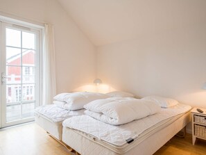 Une chambre à coucher avec un lit, une table de chevet, une lampe et une vue par la fenêtre.