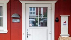 A red building with a white door, a mailbox, and a sign with a red 'A' on the wall. - 4 Star Holiday Home in Blavand (Blavand)