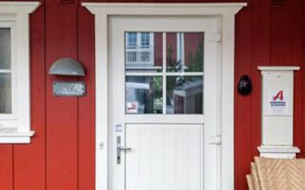 A red building with a white door, a mailbox, and a sign with a red 'A' on the wall. - 4 Star Holiday Home in Blavand (Blavand)