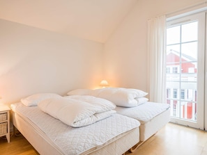 Une chambre à coucher avec un lit, une table de chevet et une fenêtre donnant sur des immeubles.