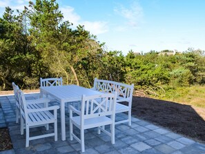 A patio with a table and chairs, surrounded by trees and a clear sky. - 5 Star Holiday Home in Norre Nebel (Norre Nebel)