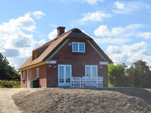 A brick house with a thatched roof, numbered 75, and a white fence in front. - 5 Star Holiday Home in Norre Nebel (Norre Nebel)
