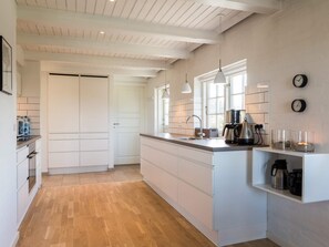 A modern kitchen with a central island, white cabinetry, and a wooden floor. - 5 Star Holiday Home in Norre Nebel (Norre Nebel)