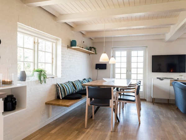 A modern kitchen with a wooden dining table, built-in bench, and pendant lighting. - 5 Star Holiday Home in Norre Nebel (Norre Nebel)