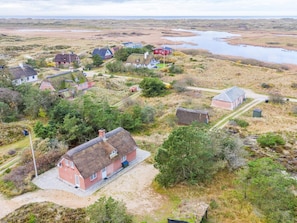 A coastal village with traditional houses, a thatched-roof building, and a body of water in the background. - 5 Star Holiday Home in Norre Nebel (Norre Nebel)