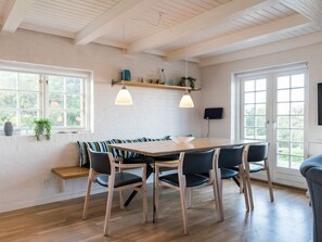 A dining area with a wooden table and chairs, a bench, and pendant lighting. - 5 Star Holiday Home in Norre Nebel (Norre Nebel)