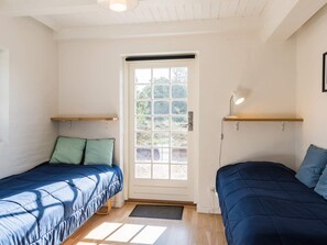 A room with two beds, a door with a window, and a desk with a lamp. - 5 Star Holiday Home in Norre Nebel (Norre Nebel)
